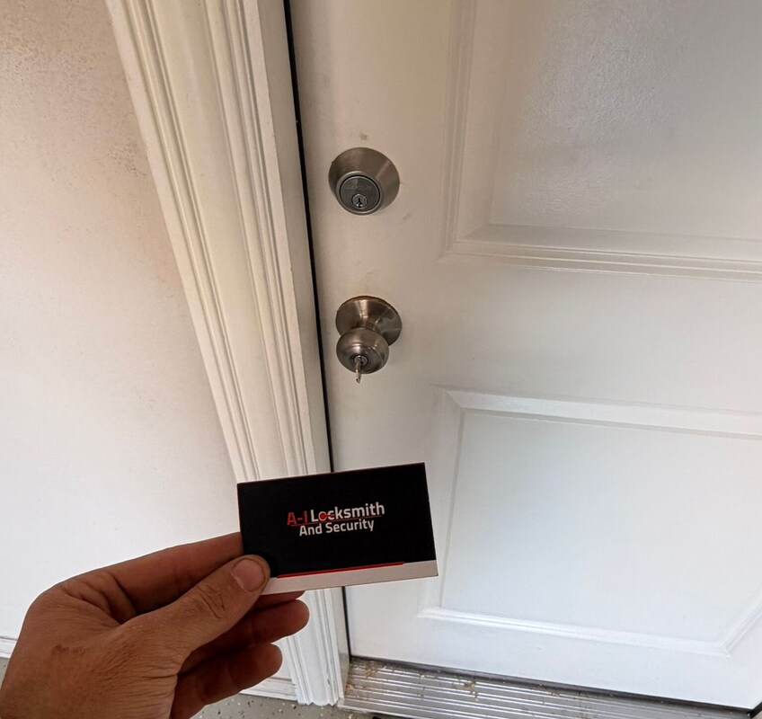 A-I Locksmith And Security technician rekeying a residential deadbolt and door knob on a white entry door.