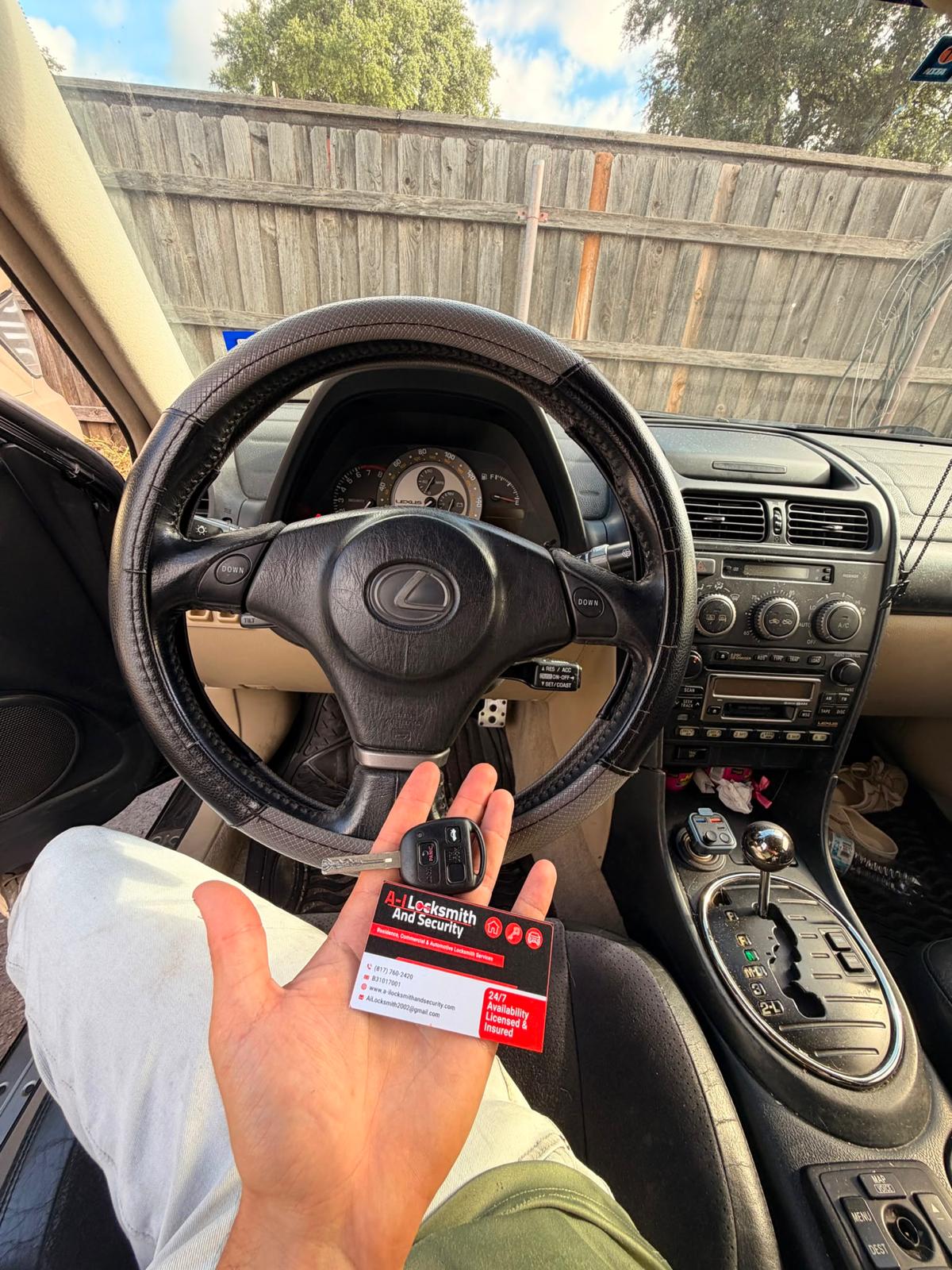 Lexus key and A-I Locksmith business card inside a vehicle