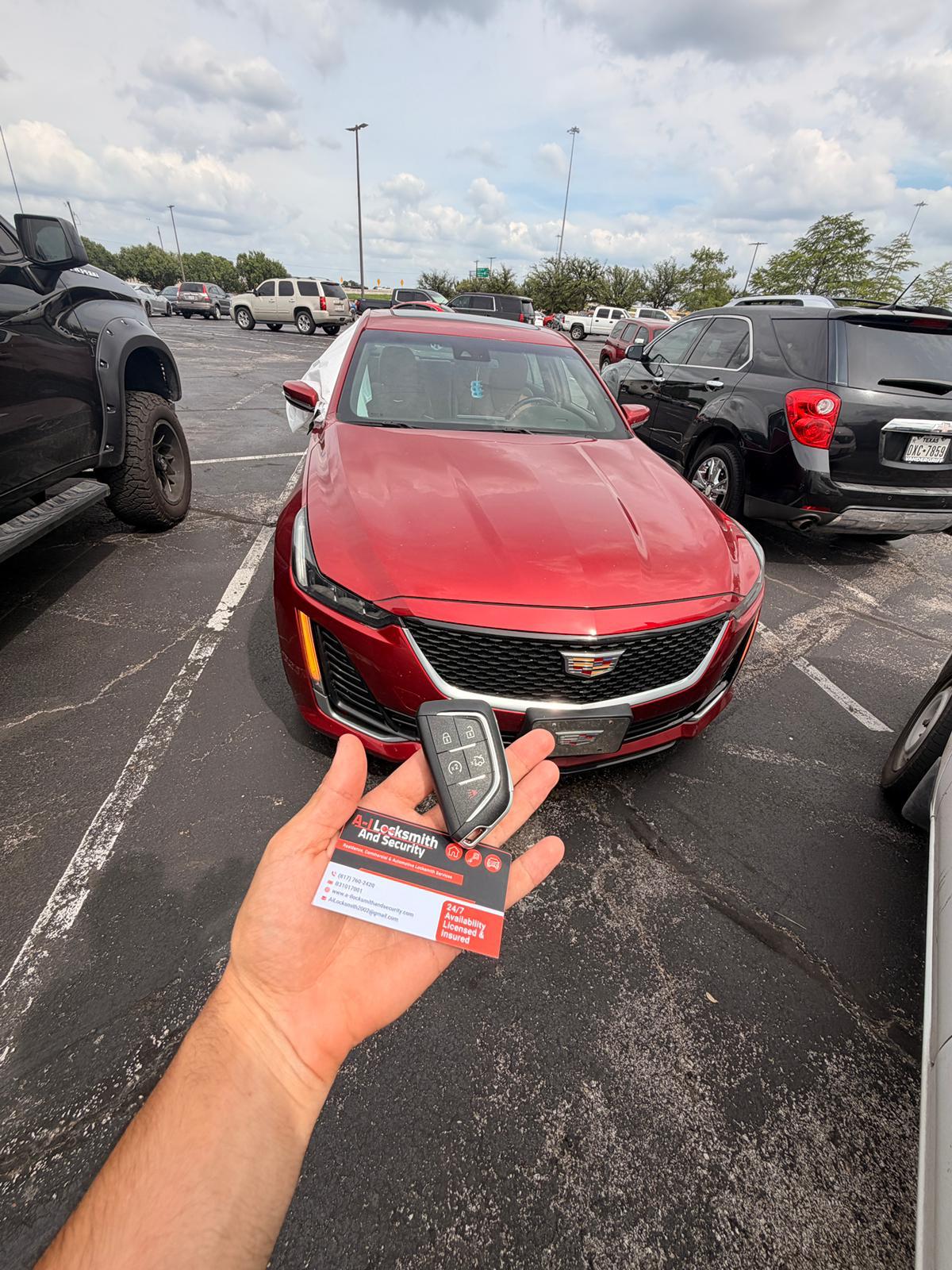 Cadillac key fob held in front of a red Cadillac